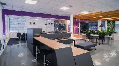 Auf einem Slider wird eine Vorher-Nachher-Ansicht einer Büroumgebung namens Arena Area erzeugt. Auf dem Vorher-Bild ist alles in kalten Farbtönen gehalten, es gibt große weiße Schreibtische mit Trennwänden und schwarze Bürostühle. Dekoration ist keine zu sehen. Auf dem Nachher-Bild ist derselbe Raum in warmen Tönen wie lila und dunkelgrau gestaltet. Es sind verschiedene Sitzmöglichkeiten wie Bänke und hohe Stühle zu erkennen. Viele grüne Pflanzen sind zu sehen.