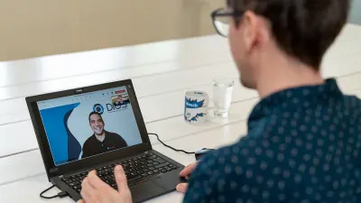 Enrico makes a video call with his colleague Burno, who can be seen on the laptop screen.