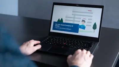 Enrico's hands are next to his laptop which shows a presentation on the Bosch company ID card project on its screen.