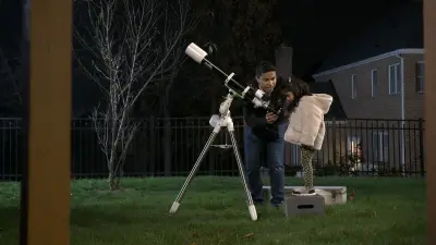 Samarjit Das und seine kleine Tochter sind zusammen im Garten. Er hilft ihr, durch ein Teleskop zu schauen.