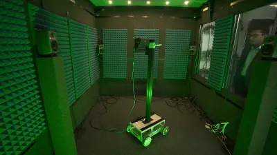 Samarjit Das schaut durch eine Scheibe in einen schallgedämmten Raum. Darin ist der Akustik-Sensor SoundSee auf einem Gefährt installiert.
