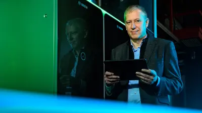 Bernd Schulte-Sprenger, Vorsitzender der Geschäftsführung der PASM, steht vor zwei SOFC-Anlagen und hat ein iPad in der Hand.