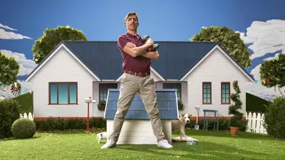Shawn poseert in de voortuin voor een hondenhok met zijn boorgereedschap in de hand.