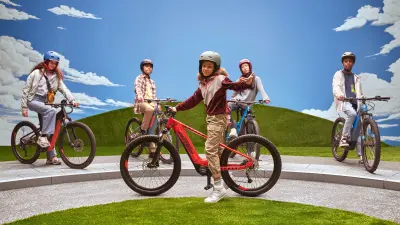 Shawna poseert voor haar eBike terwijl je haar vrienden op eBikes op de achtergrond kunt zien.