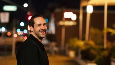 Michael Johnson strolls down Euclid Avenue in Ontario. It is nighttime. He turns toward the camera with a broad smile.