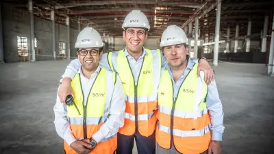 The managing directors responsible for BSH in Egypt are CEO Luis Alvarez (right), CTO Mourad Gendy (center) and CFO Ahmed Riad (left). They are standing in the future production hall wearing high-visibility vests and hard hats. The hall is under construction and can be seen blurred in the background.
