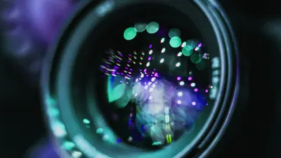 The close-up shot of a camera lens with lights playing off of it.