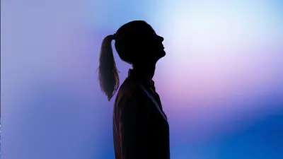 The silhouette of a woman with a ponytail against a blurred background. 