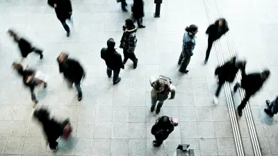 Several passersby walking through a square.