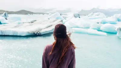 A woman standing in front of a glacial lake. 