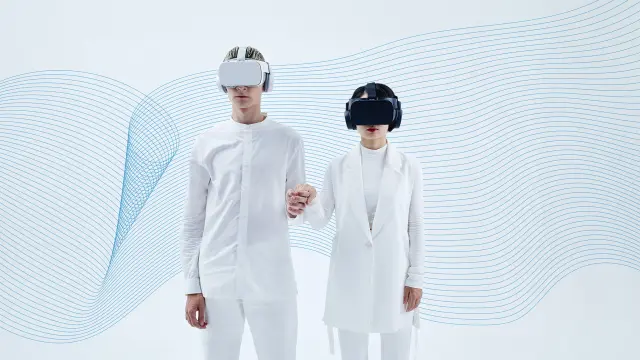 A couple wearing VR goggles dressed in white holding hands.