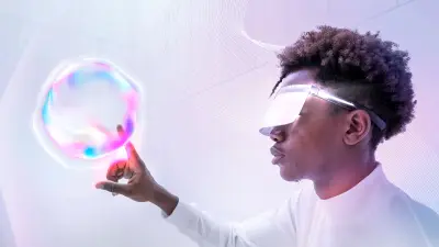 Ein Mann mit einer futuristischen Brille berührt mich seinem Finger einen schwebenden Ball in Hologramm-Optik.