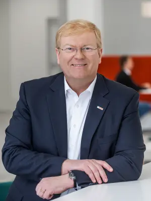 Stefan Hartung in einem modernen Büro, lächelnd und entspannt.