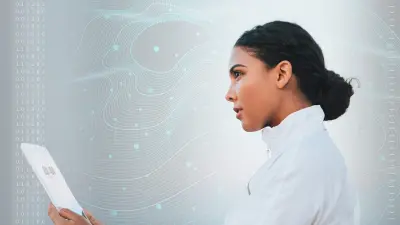Eine Frau steht vor einer digitalen Wand mit abstrakten Datenmustern. In ihrer Hand hält sie ein Tablet. Sie schaut zuversichtlich.