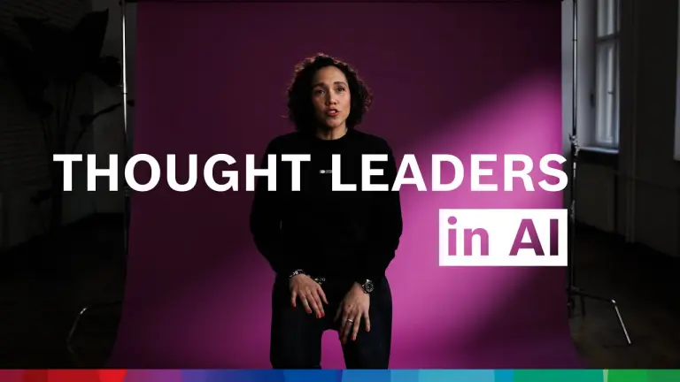 Nicole Büttner sits on a chair and speaks into the camera, in front of her the words “Thought Leader in AI”.