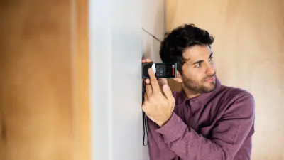 Architect Leonardo Di Chiara stands in his tiny house and measures a distance using the PLR 50 C digital laser measure from Bosch.
