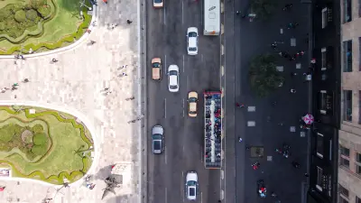AIoT im Straßenverkehr: Der Stau auf einer stark befahrenen Straße lichtet sich. Links der Straße liegt eine Parkanlage, rechts eine Fußgängerzone.