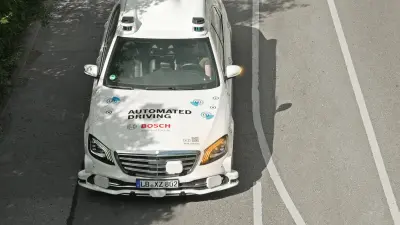 A self-driving car equipped with various sensors travels on a road. It activates the left blinker to initiate the lane change on its own.