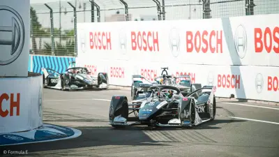 Several electric racecars can be seen on a racetrack. They’re driving past Bosch billboards.