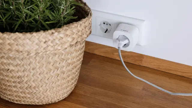 We see the Plug Compact from Bosch plugged into a socket with a cable.