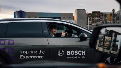 A car drives along a road, with a person inside the car