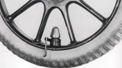 Lower half of a wooden wheel with bell-shaped attachment on the rim.