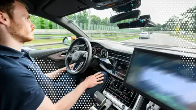 Ein Fahrer sitzt am Steuer eines Autos auf der Autobahn; eine transparente digitale Überlagerung mit quadratischen Pixelcodes liegt über dem Displaybereich.