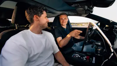 Ein Auto fährt auf einer Landstraße, darin befinden sich zwei Personen