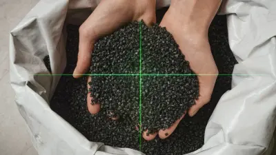 Nahaufnahme, auf der schwarzes Granulat aus recyceltem Kunststoff in zwei Händen liegt