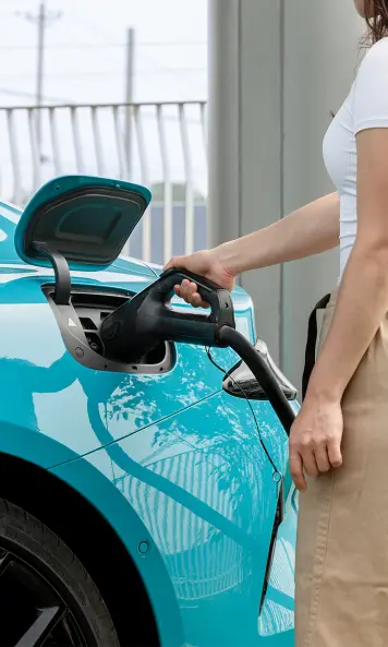 Eine Frau lädt ein Elektrofahrzeug Xiaomi SU7 an einer Ladestation auf.