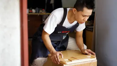Der Handwerker Brian Tan vergleicht zwei Holzstücke.