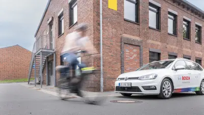 Bosch research vehicle and an eBike dummy on a test track demonstrate V2X technology preventing a collision.