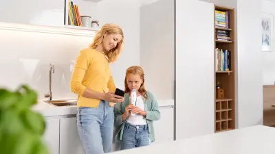 A mother and child in kitchen using breath device, smartphone in hand