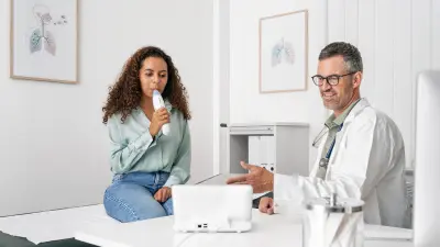 Person using breath device in clinic, medical staff pointing at tablet