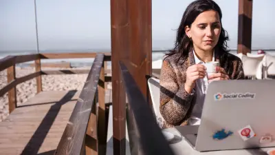 Soraia in einem Café am Strand mit ihrem Laptop.