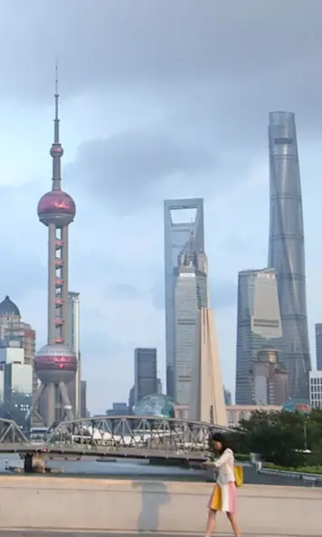 The image shows a woman with a smartwatch in front of the sykline of shanghai.