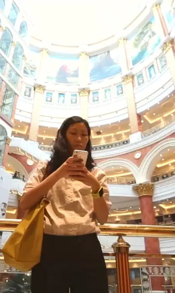 The image shows a woman with smartwatch and smartphone in a mall.