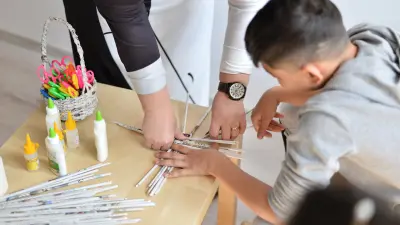 A boy doing handicrafts with a second person.